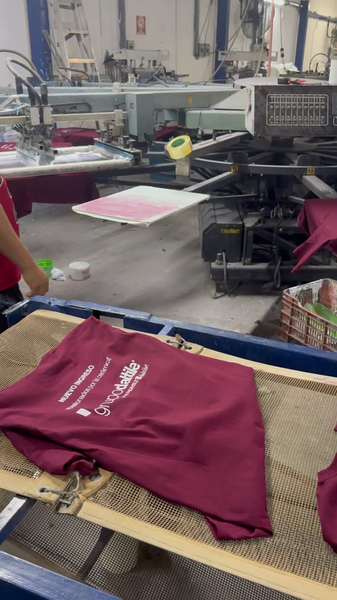 Playera color vino recién impresa sobre la banda del horno de curado